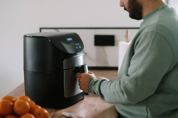 A young man cooking using an air fryer