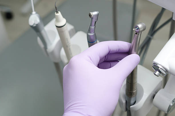 Hand of dentist holding dental drill machine with turbine