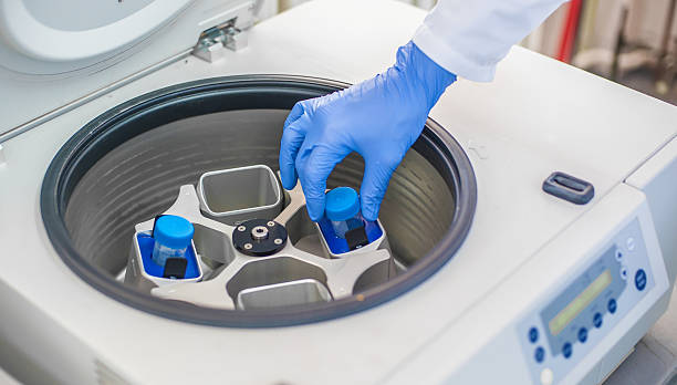 Technician loading a sample to centrifuge machine in the medical or scientific laboratory